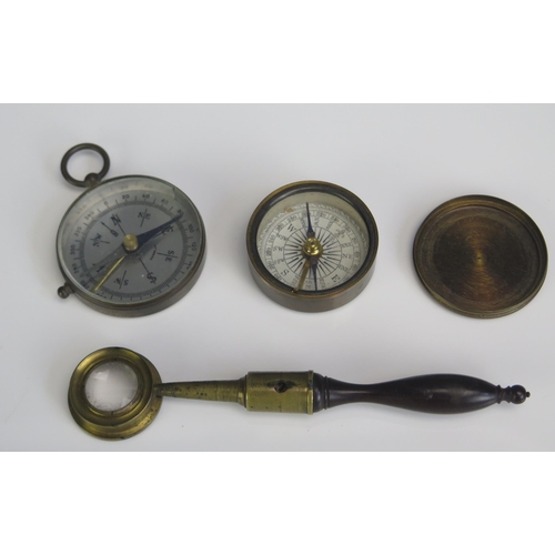 1569 - A 19th century magnifying glass with turned wood handle, together with two pocket compasses. (3).