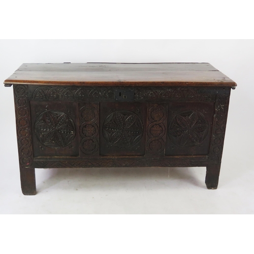 1573 - An 18th Century carved oak coffer of rectangular outline, with triple carved panel front, raised on ... 