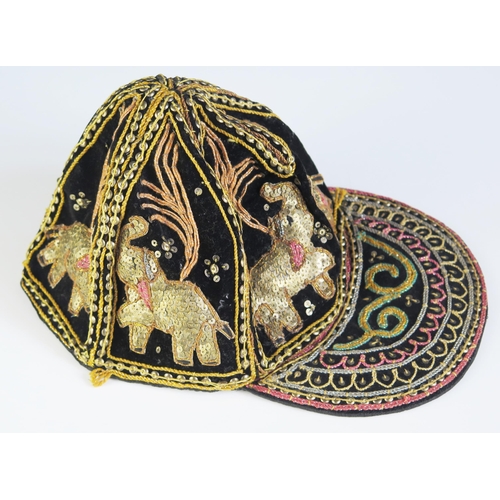 1616 - An Indian black silk and velvet cap with applied sequin decoration in the form of elephants.