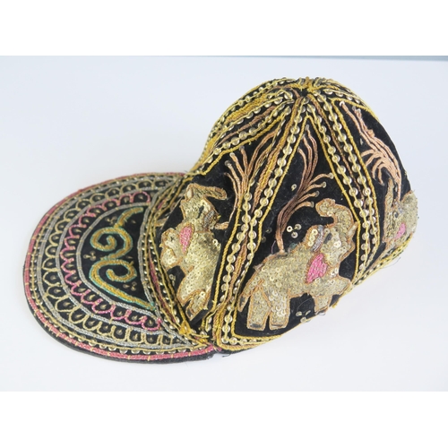 1616 - An Indian black silk and velvet cap with applied sequin decoration in the form of elephants.