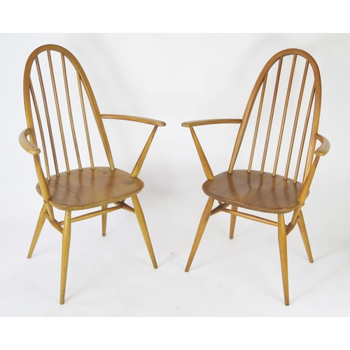 1634 - A pair of Ercol Quaker elbow chair with arched backs, solid seats on turned legs.