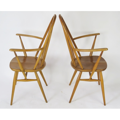 1634 - A pair of Ercol Quaker elbow chair with arched backs, solid seats on turned legs.