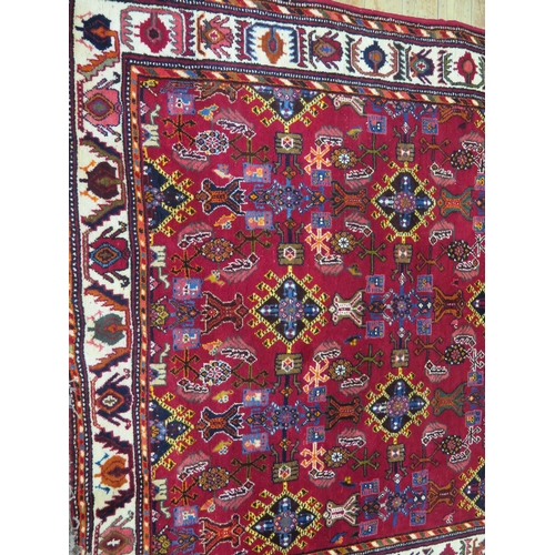 1689 - A Qashgai rug, the wine red field with rows of hooked medallions, enclosed by a main ivory triple ge... 