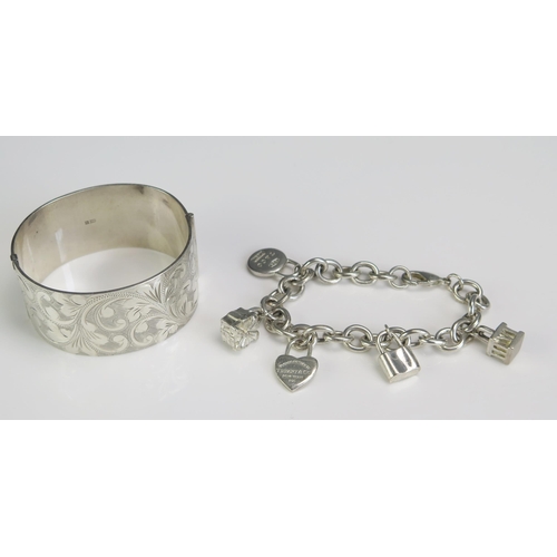 280 - A Silver Hinged Bangle with chased foliate decoration and a Tiffany silver charm bracelet, 11.92g