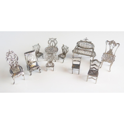 519 - A collection of English and continental silver miniature furniture, includes filigree love seat, sid... 