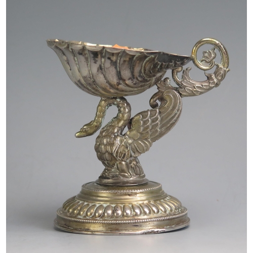 688 - A continental white metal pedestal salt, the shell shaped dish supported on a winged griffon and dom... 