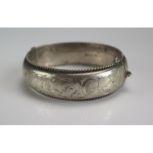 208 - A Silver Hinged Bangle with chased foliate decoration, Chester 1957, 29g