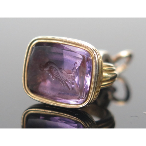 129 - An Antique Amethyst Seal in a precious yellow metal setting, the matrix carved with a bird, 26.1mm d... 