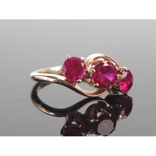 17 - A 9ct Gold and Ruby Three Stone Ring, largest stone c. 5.6mm, size M.5, stamped 9CT, 3.75g