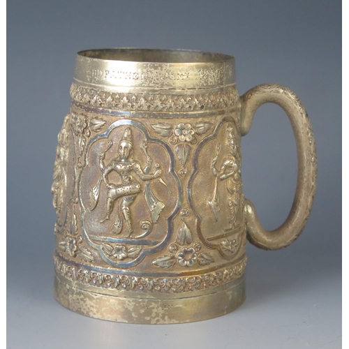 579 - A late Victorian Indian silver mug of cylindrical form, with embossed panels decorated with dancers ... 