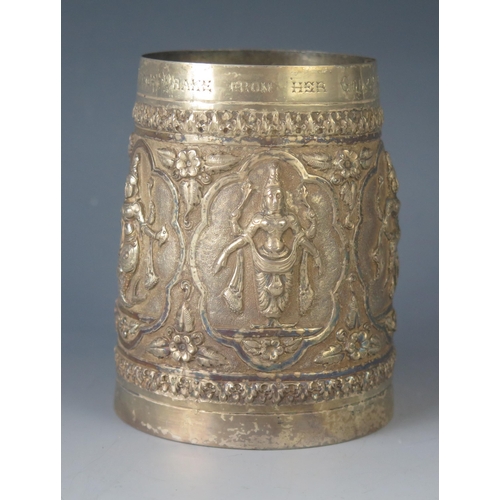 579 - A late Victorian Indian silver mug of cylindrical form, with embossed panels decorated with dancers ... 