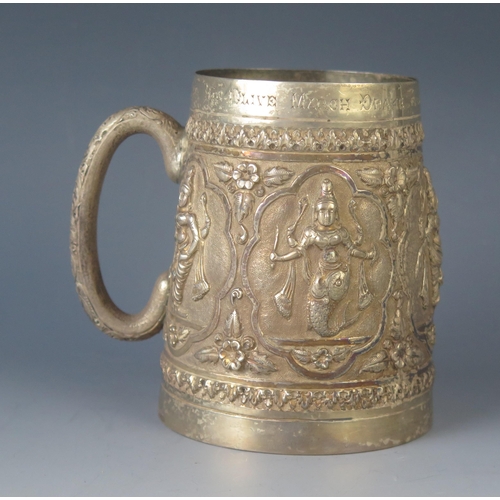 579 - A late Victorian Indian silver mug of cylindrical form, with embossed panels decorated with dancers ... 