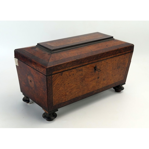 1061 - A 19th century figured walnut and tea caddy of sarcophagus outline, with shallow domed hinged lid en... 