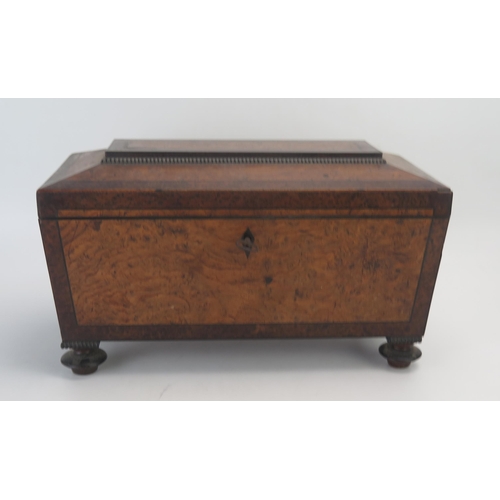 1061 - A 19th century figured walnut and tea caddy of sarcophagus outline, with shallow domed hinged lid en... 