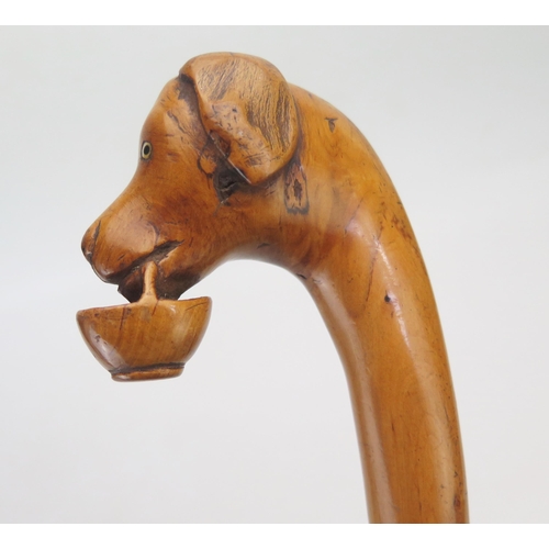 1087 - A carved hardwood walking stick, the handle carved with a dog's head holding a basket.