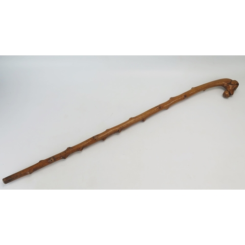 1087 - A carved hardwood walking stick, the handle carved with a dog's head holding a basket.