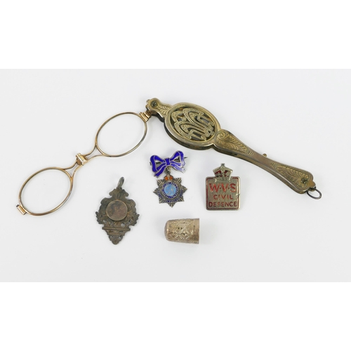 1103 - A pair of gilt metal lorgnettes with press -button action, silver fob, thimble and two badges.