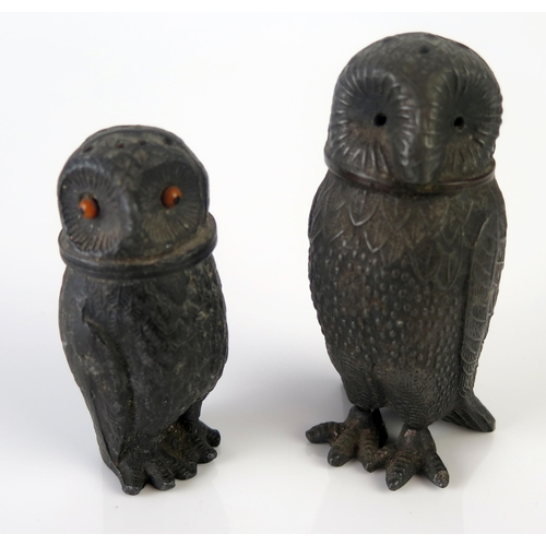 1191 - A pair of metal pepperettes in the form of owls, one with inset glass eyes, 10cm and 8cm high.