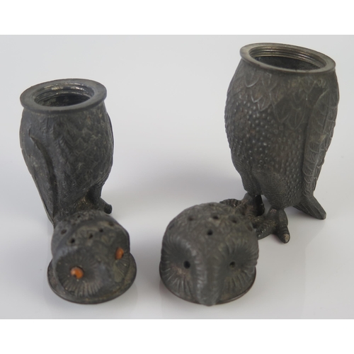 1191 - A pair of metal pepperettes in the form of owls, one with inset glass eyes, 10cm and 8cm high.