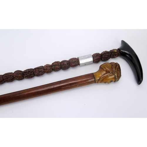 1199A - A Malacca walking cane , the pommel carved in the form of a head, together with a nut mounted walkin... 