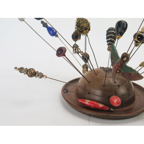 1274 - A collection of Victorian and later hat pins, mounted in a turned wood hat pin holder.