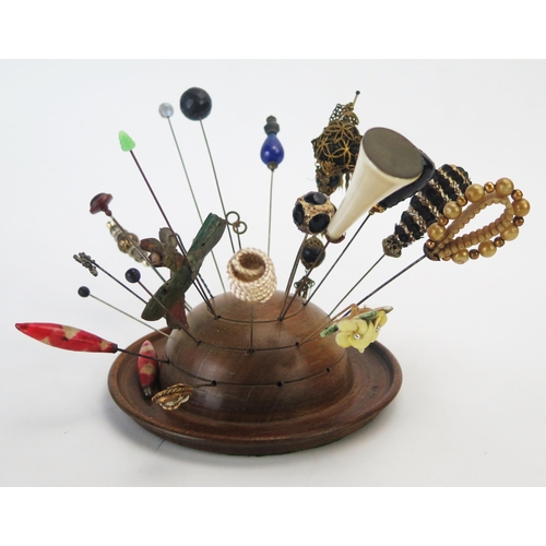 1274 - A collection of Victorian and later hat pins, mounted in a turned wood hat pin holder.