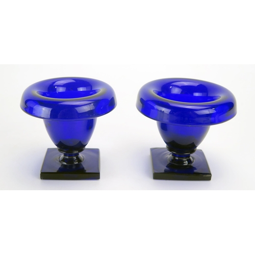 1290 - A pair of Bristol blue glass pedestal salts, of urn-shaped outline on square bases, 8cm high.