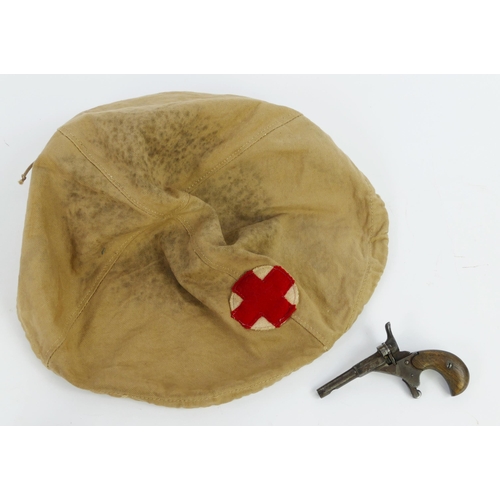 1355 - A World War I or II canvas Red Cross helmet cover, together with a starting pistol.