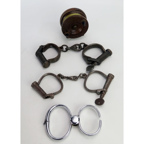 1375 - Three pairs of steel handcuffs, together with a mahogany half starback fishing reel. (4)