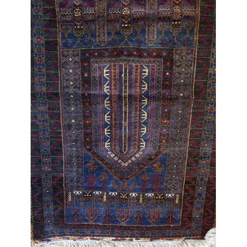 1391 - A Caucasian prayer rug, the main wine red geometric field with arched mirab, enclosed by a triple me... 