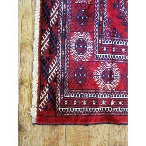 1394 - A Turkomen carpet, the wine red field with four rows of lozenge medallions, enclosed in a multiple g... 