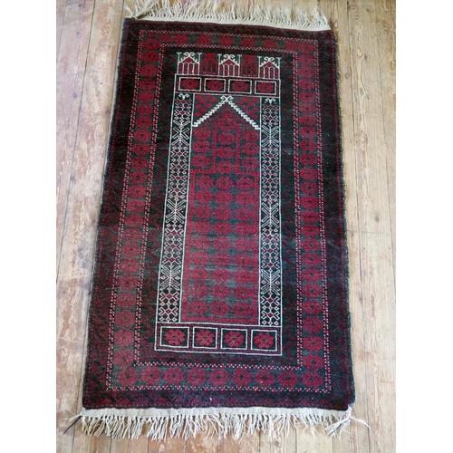 1396 - An Afghan baluch prayer rug, the wine red field with hooked and stepped mirab, enclosed by a triple ... 