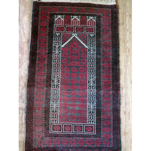 1396 - An Afghan baluch prayer rug, the wine red field with hooked and stepped mirab, enclosed by a triple ... 