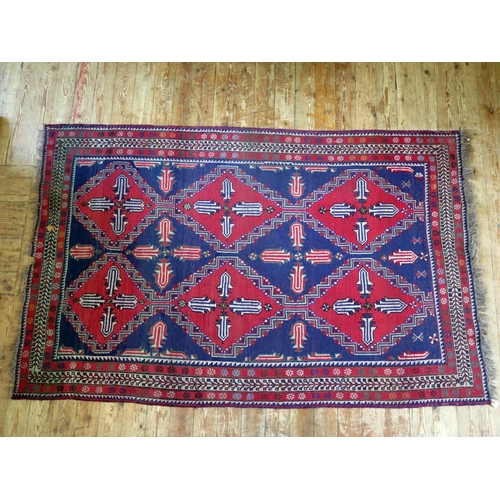 1400 - An Afghan Belouch rug, the indigo field with two rows of triple stepped wine red medallions, enclose... 