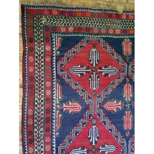 1400 - An Afghan Belouch rug, the indigo field with two rows of triple stepped wine red medallions, enclose... 