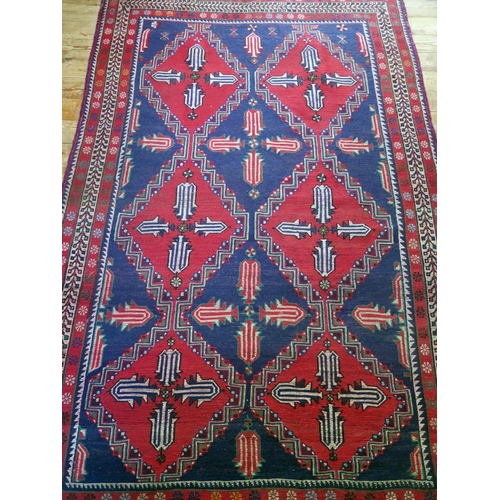 1400 - An Afghan Belouch rug, the indigo field with two rows of triple stepped wine red medallions, enclose... 