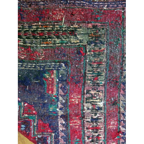 1400 - An Afghan Belouch rug, the indigo field with two rows of triple stepped wine red medallions, enclose... 