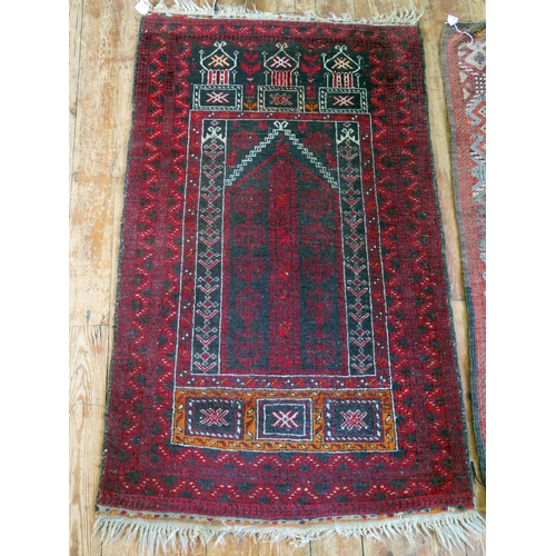 1402 - An Afghan baluch prayer rug, the wine red field with hooked and stepped mirab, enclosed by a triple ... 