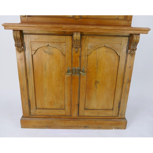 1431 - A Victorian pine dresser. the upper part with a pair of arched glazed panelled doors, the base conta... 