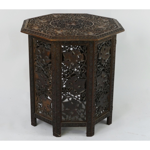 1442 - An eastern carved hardwood folding octagonal occasional table, the top decorated with foliage and fl... 