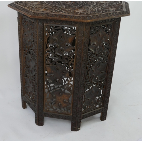 1442 - An eastern carved hardwood folding octagonal occasional table, the top decorated with foliage and fl... 