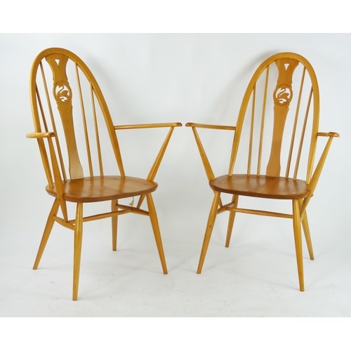 1453 - A pair of Ercol elbow chairs, the arched stickbacks with central carved swan splat above a solid sea... 