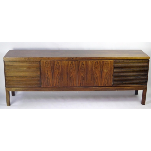 1464 - A modernist rosewood sideboard of rectangular outline, containing a pair of plain field central cupb... 