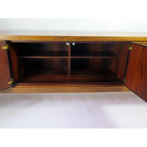 1464 - A modernist rosewood sideboard of rectangular outline, containing a pair of plain field central cupb... 