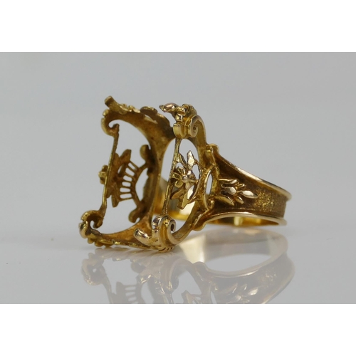 93 - A French 18ct Gold Ornate Ring Mount with a central floral basket and scrolling corners, size K.25, ... 