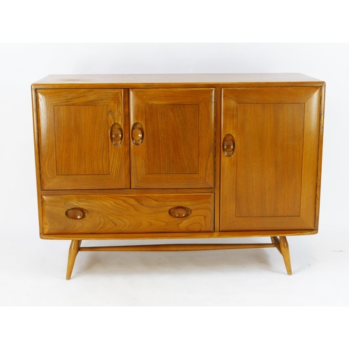 1458 - An Ercol elm and beech sideboard, fitted with cupboards and single drawer, enclosed by panelled door... 