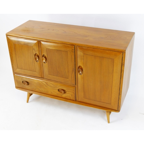 1458 - An Ercol elm and beech sideboard, fitted with cupboards and single drawer, enclosed by panelled door... 