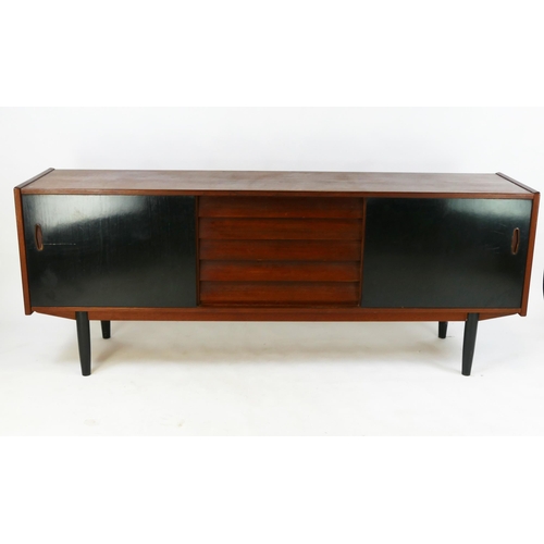 1475 - A 1960's teak sideboard, containing five short drawers, flanked by two sliding doors, on turned and ... 