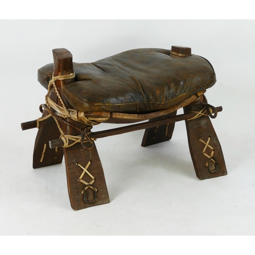 1484 - A camel saddle of traditional design with hide cushion seat, 74cm long, 55cm high.