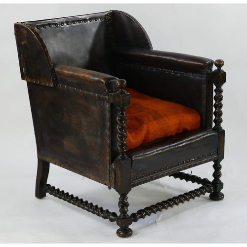 1495 - An Edwardian oak and leather upholstered armchair, with wing back, padded arm rests, loose cushion